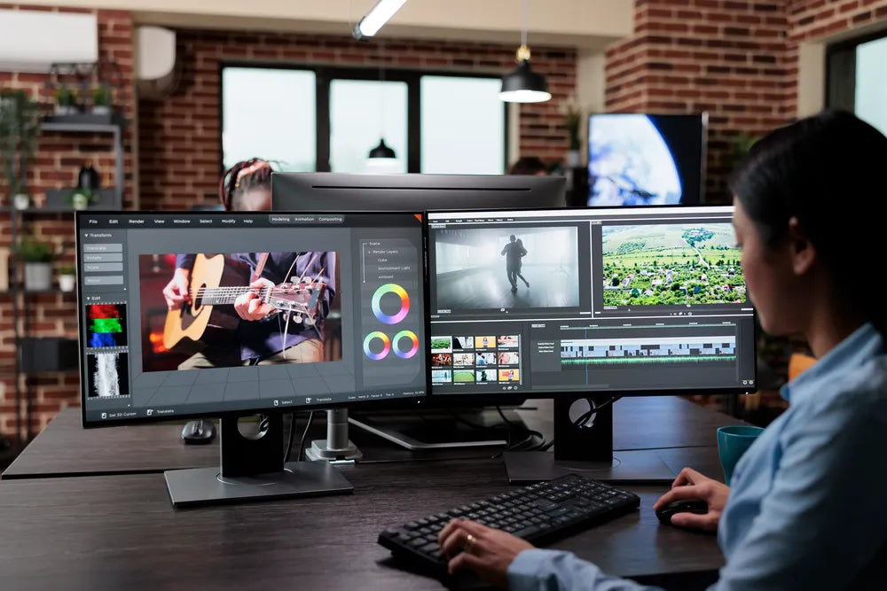 Professional using a dual monitor setup for graphic design and creative work with ergonomic monitor stands.